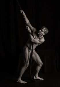 Nude figure leaning back and pulling a thick rope, body angled and looking up along the line.